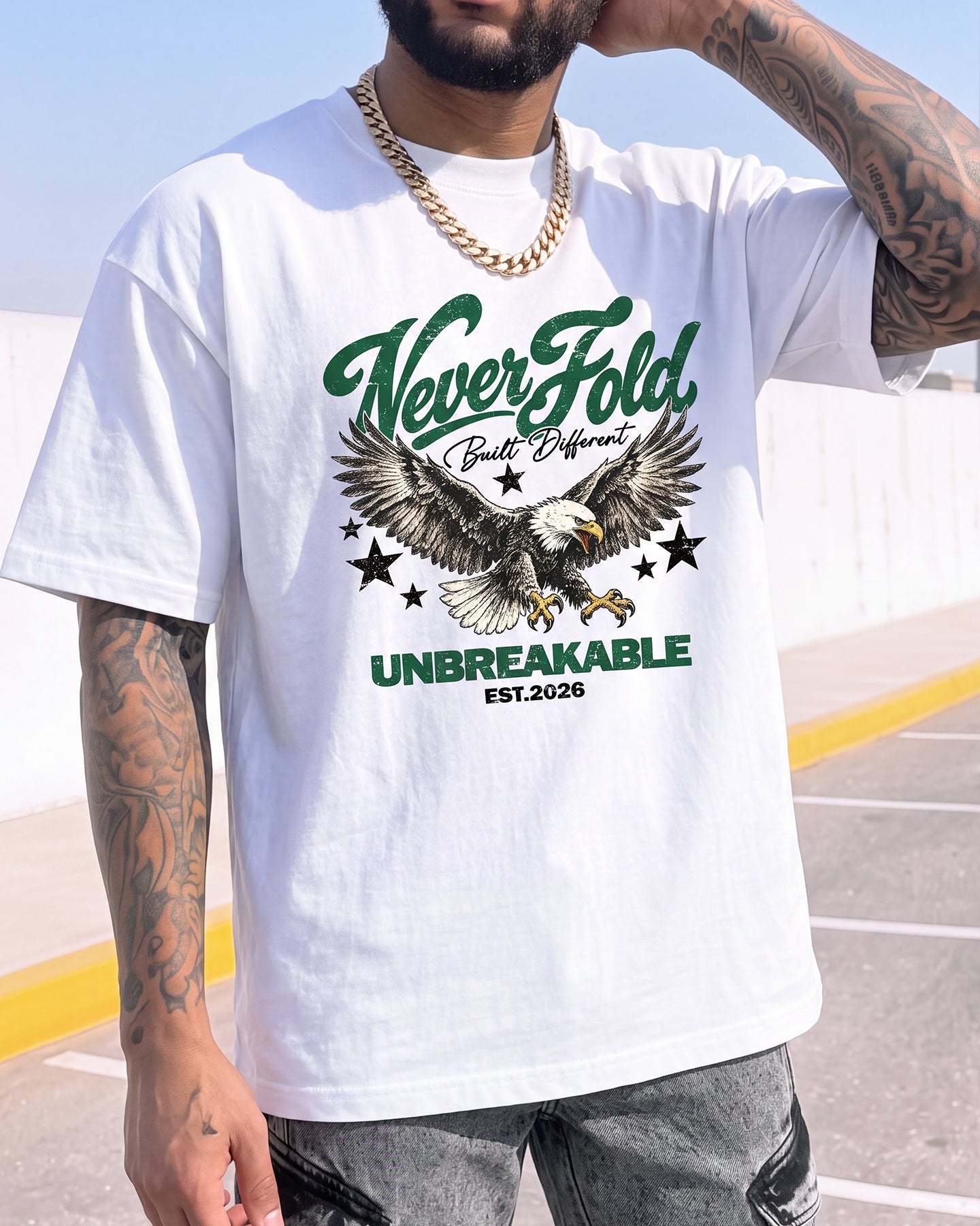 A man wearing a white graphic t-shirt with a green and black eagle design and the text 'Never Fold. Built Different.