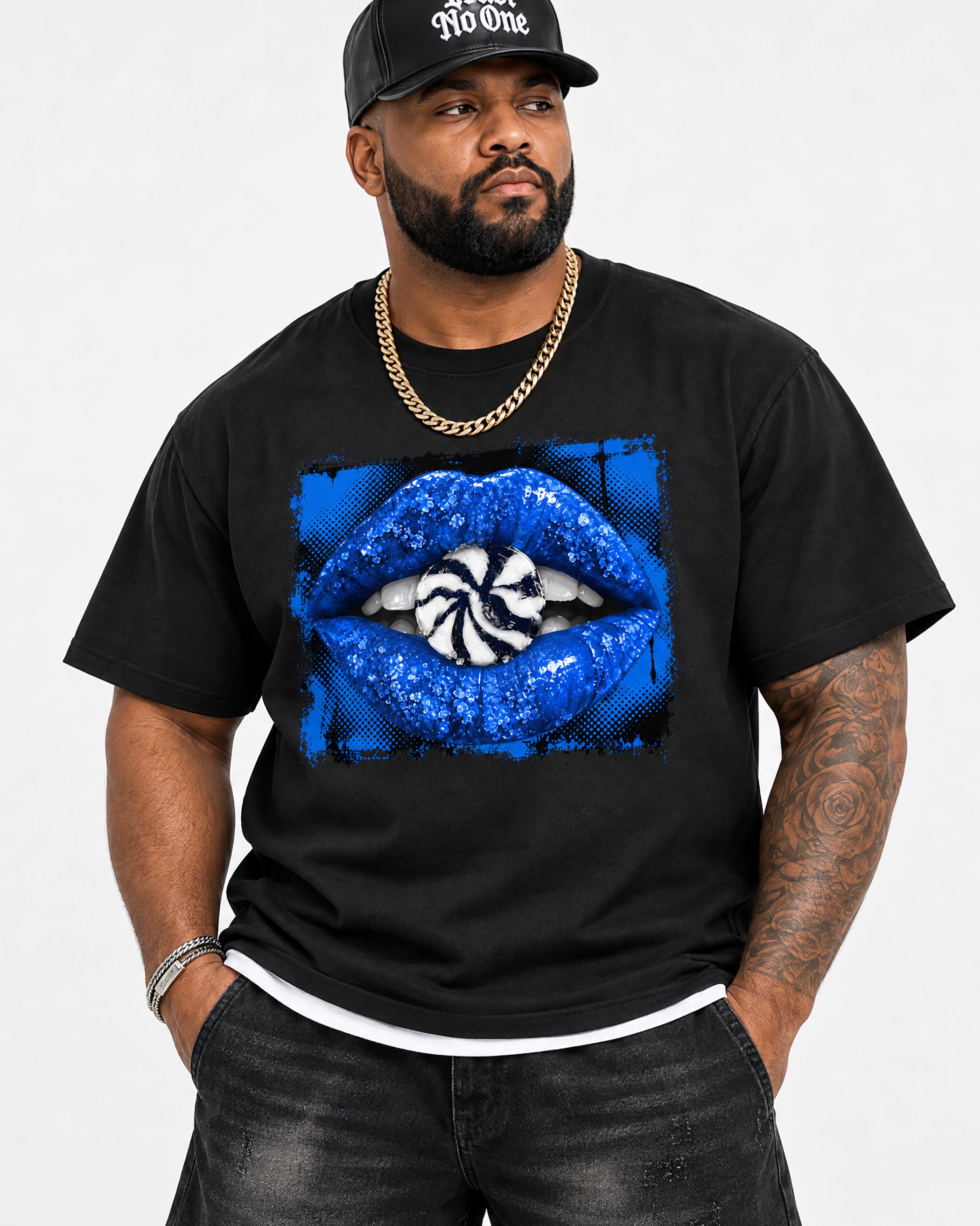 A man wearing a black t-shirt with a blue sequined lips graphic on the front, paired with a black cap and gold chain, photographed against a plain white background.