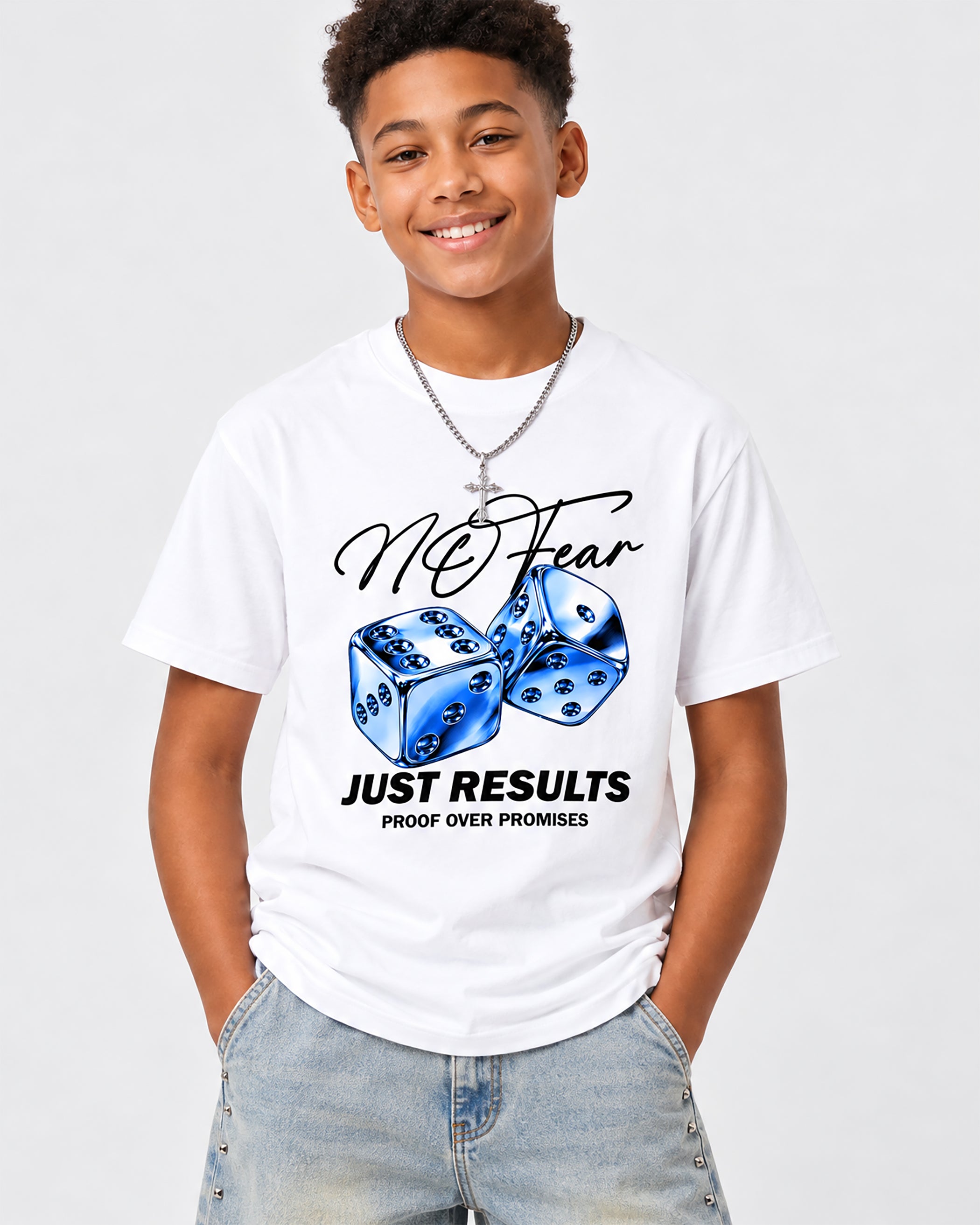 A smiling young man wearing a white graphic t-shirt with a blue dice design and the text 'McFear JUST RESULTS PROOF OVER PROMISES', paired with light-wash jeans and a silver necklace, against a light gray background.