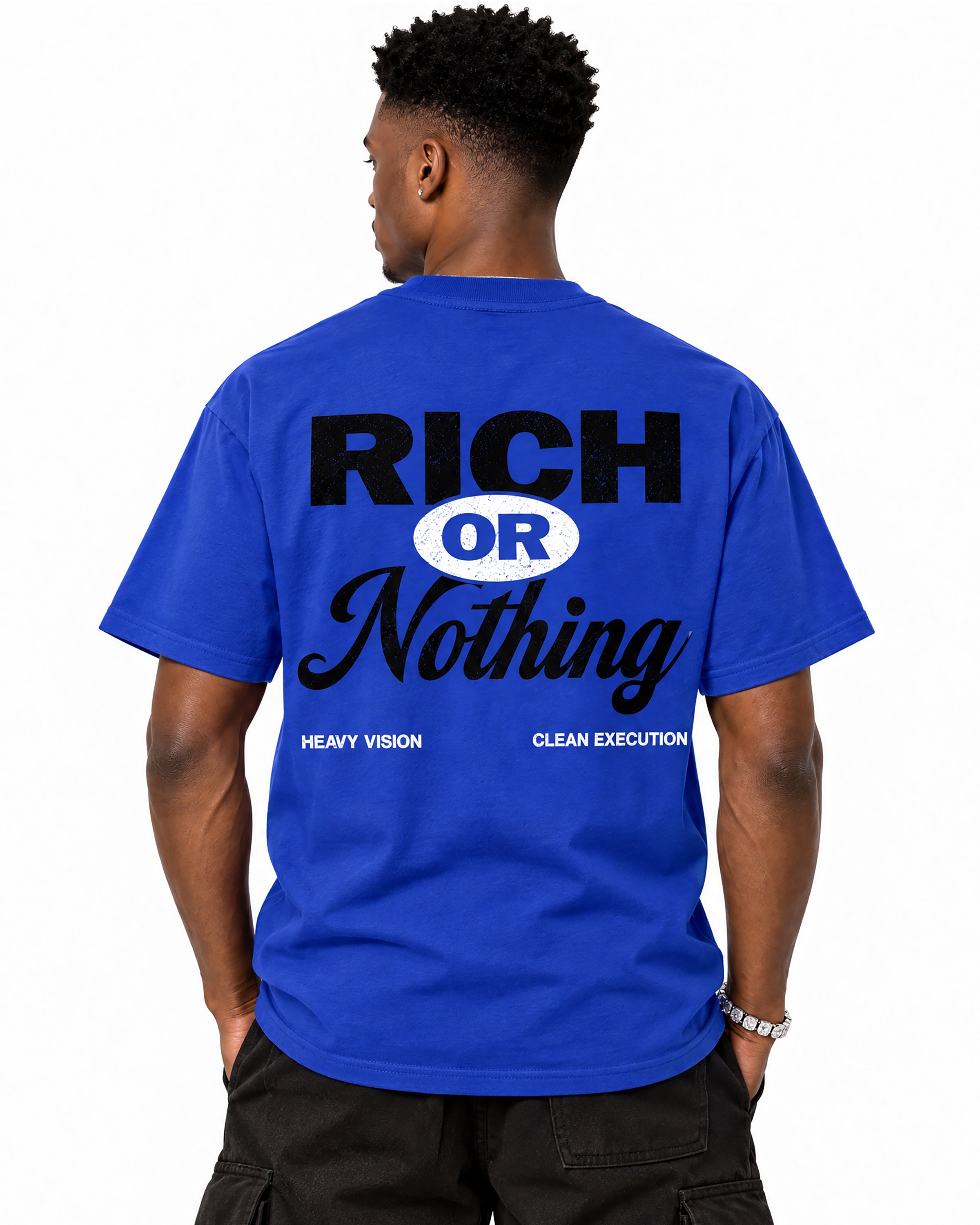 A man viewed from the back wearing a royal blue t-shirt with a bold graphic print reading 'RICH OR Nothing' in black and white, paired with black cargo pants against a plain white background.