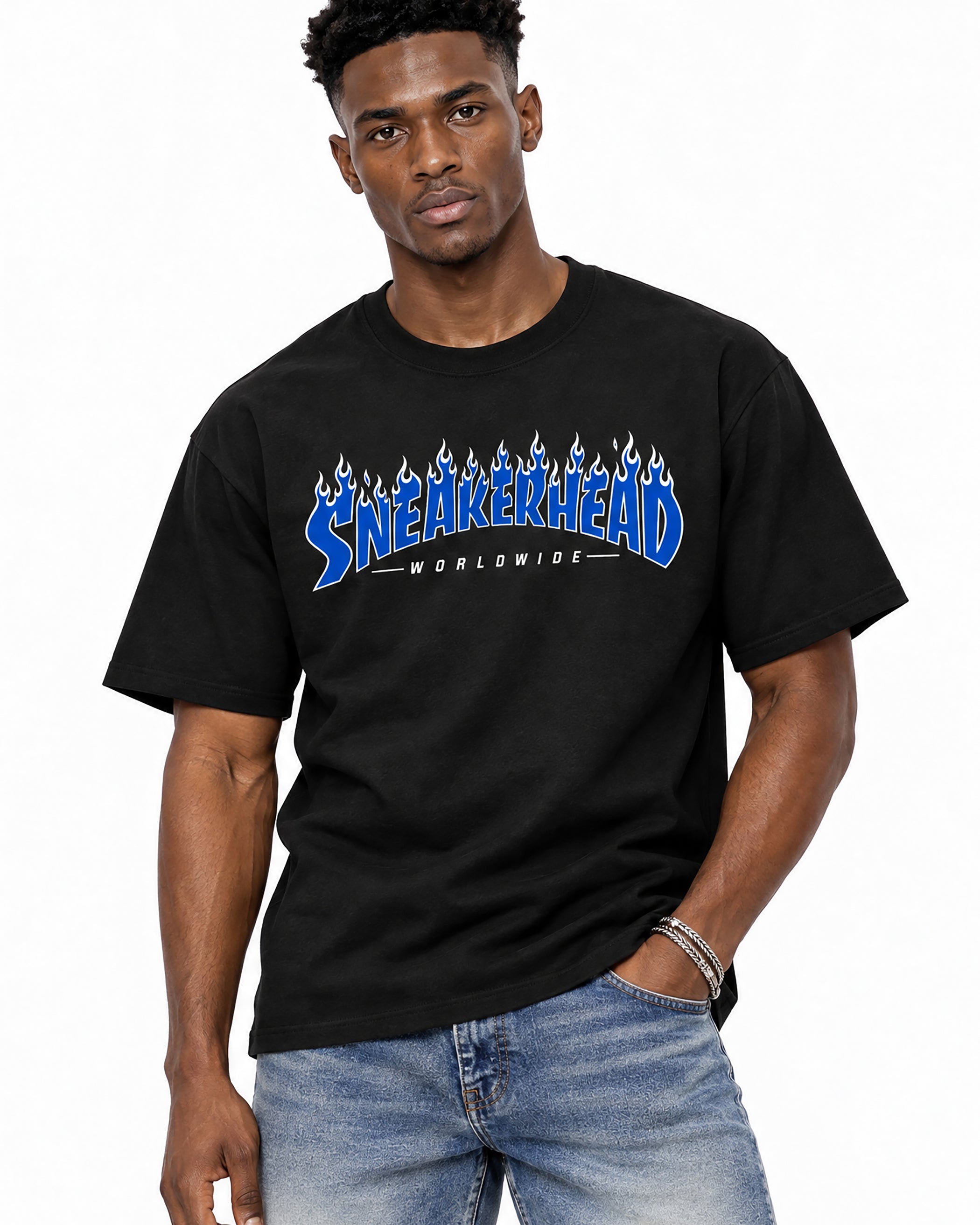 A man wearing a black crewneck t-shirt with a blue and white 'Sneakerhead Worldwide' graphic across the chest, paired with blue jeans, against a plain white background.