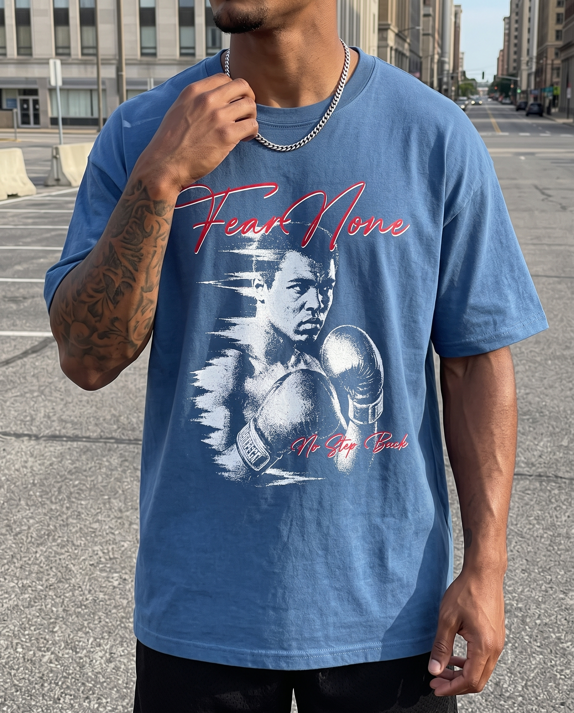 A man wearing a blue graphic t-shirt featuring a stylized white boxing portrait of Muhammad Johnson with red script text reading 'Fear None' and 'Mr. Fight Back'.