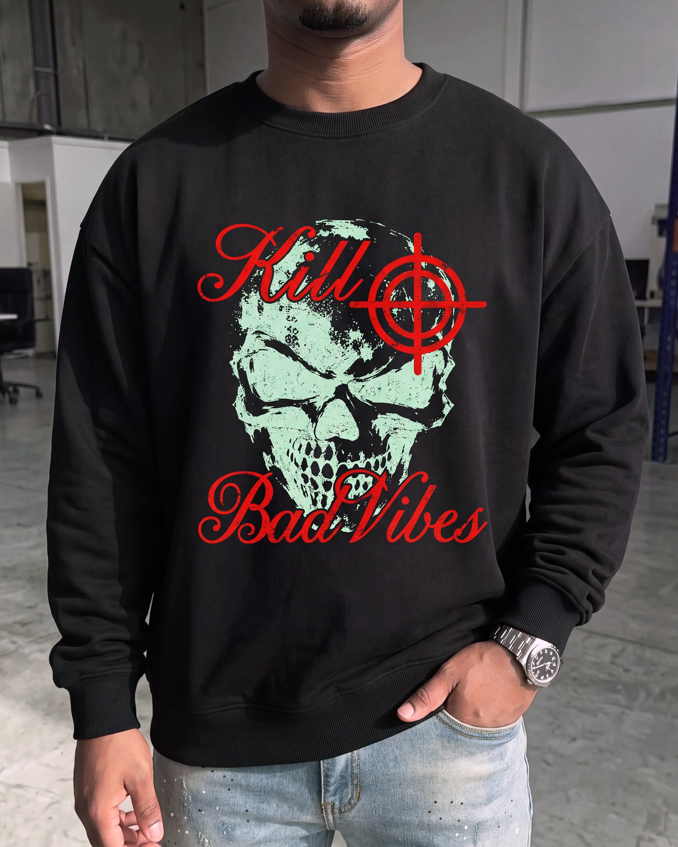 A man wearing a black crewneck sweatshirt with a graphic print of a skull and the text 'Kill Bad Vibes' in red, paired with light blue jeans.