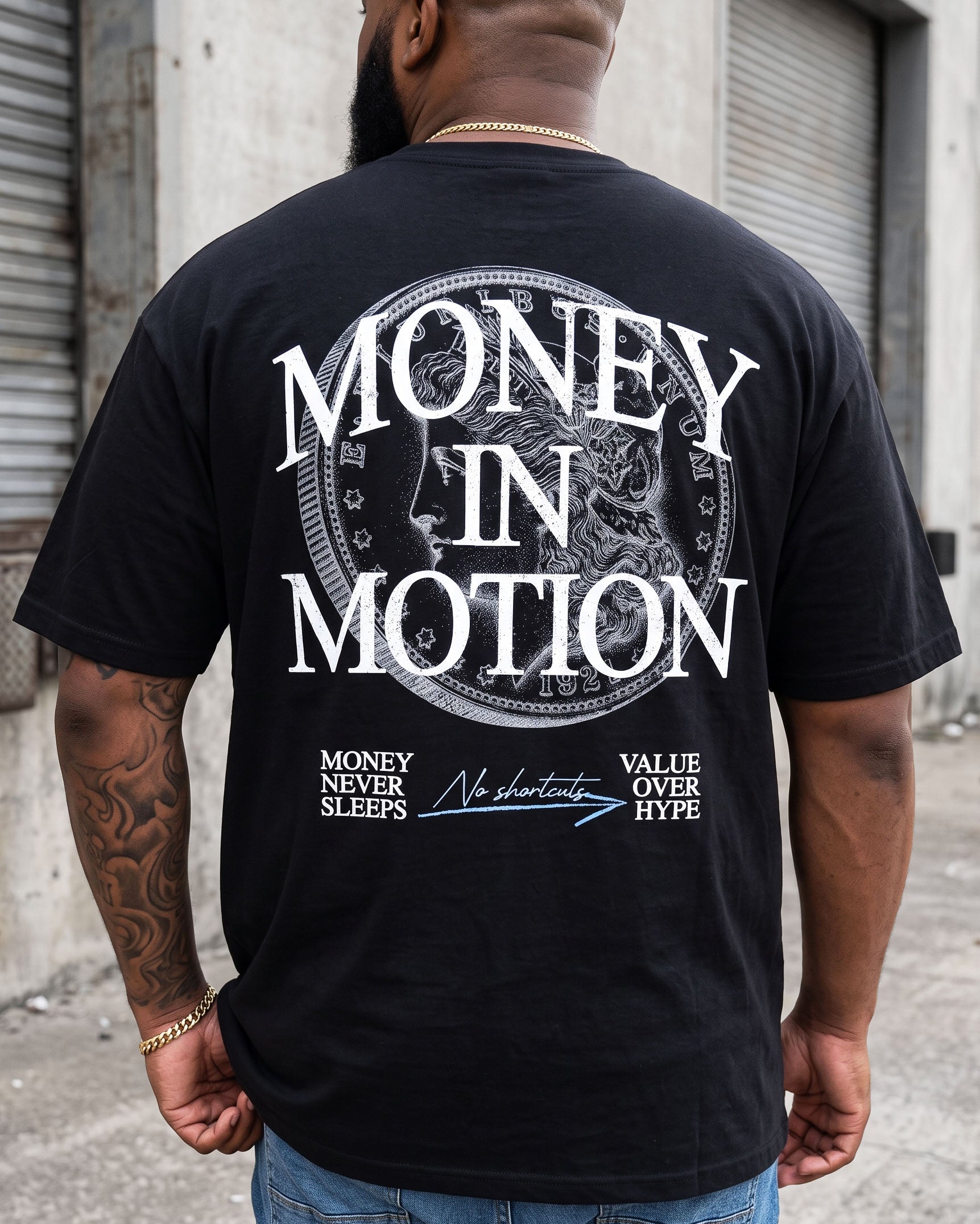 A man viewed from behind wearing a black t-shirt with a large white graphic print on the back that reads 'MONEY IN MOTION' inside a circular emblem, with smaller text below, set against an urban alley background.