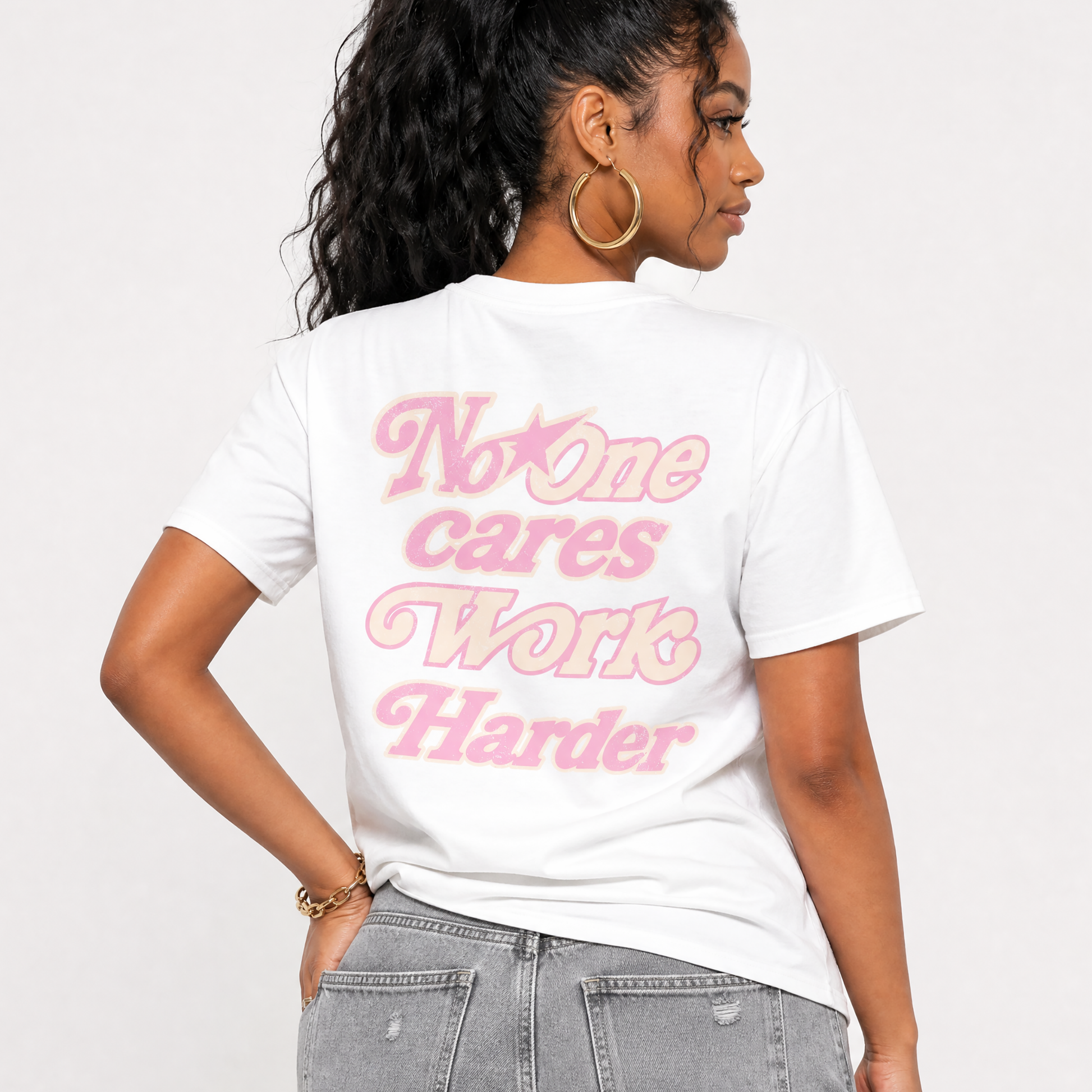 Person wearing a white t-shirt with no one cares work harder text on a plain background