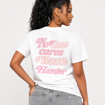 Person wearing a white t-shirt with no one cares work harder text on a plain background