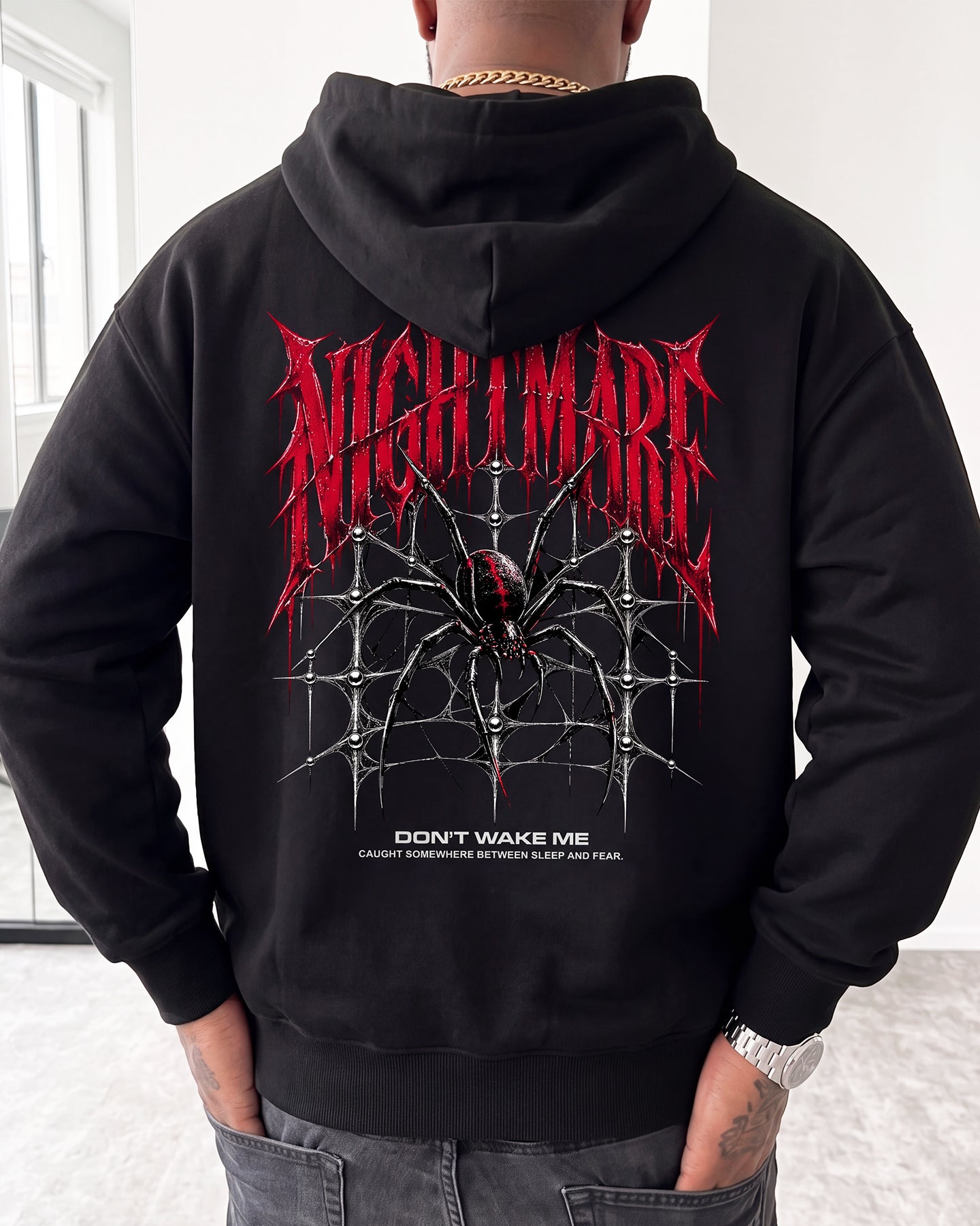A person shown from the back wearing a black hoodie with a large red and white spider-themed graphic and the word 'NIGHTMARE' across the upper back.