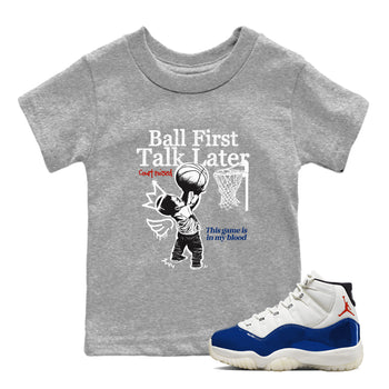 Gray t-shirt with basketball graphic and text, paired with a white and blue sneaker.
