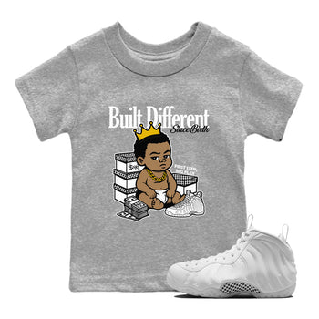 Built Different Since Birth baby and kids t-shirt crafted for little sneakerheads to shine with the Air Foamposite One Triple White sneakers, displayed in Heather Grey 1.