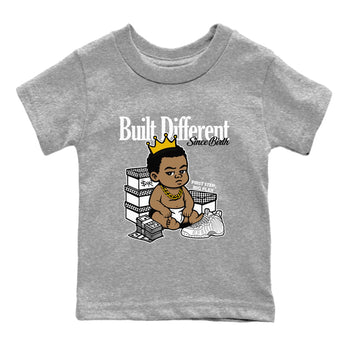 Built Different Since Birth baby and kids t-shirt crafted for little sneakerheads to shine with the Air Foamposite One Triple White sneakers, displayed in Heather Grey 2.