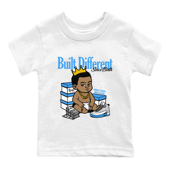 Built Different Since Birth baby and kids t-shirt crafted for little sneakerheads to shine with the Air Jordan 12 White and University Blue sneakers, displayed in White 2.