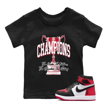 Champions Trophy baby and kids t-shirt crafted for little sneakerheads to shine with the Air Jordan 1 Ruby sneakers, displayed in Black 1.