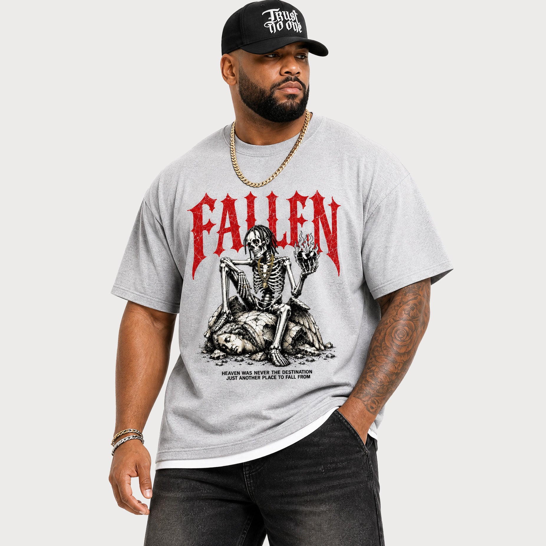A man wearing a light gray heather t-shirt with a red 'FALLEN' band graphic and a skeleton illustration, paired with a black baseball cap and black jeans, against a light gray background.