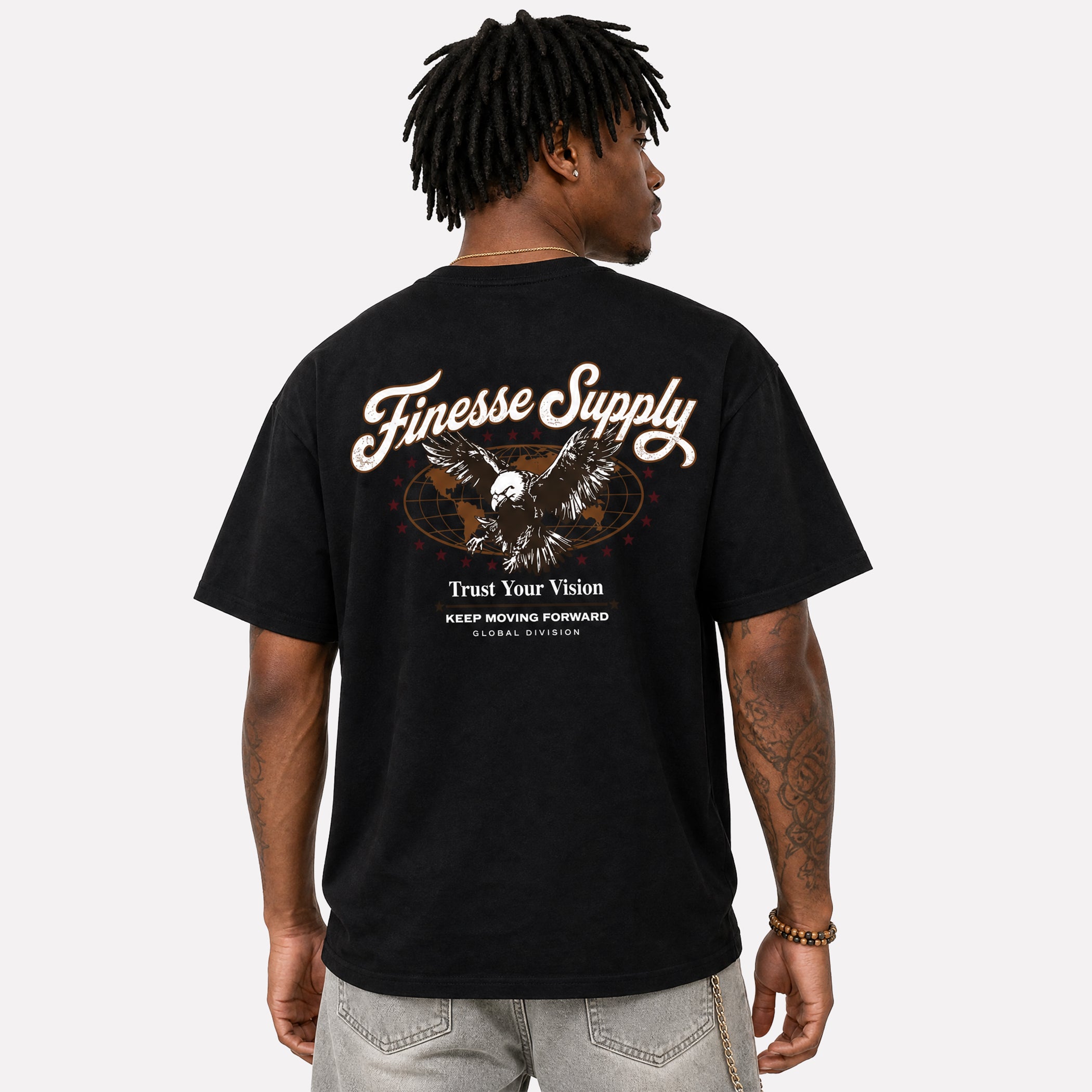 A man shown from the back wearing a black Finesse Supply graphic t-shirt with a large eagle and text design on the back, paired with light gray jeans, against a light gray studio background.