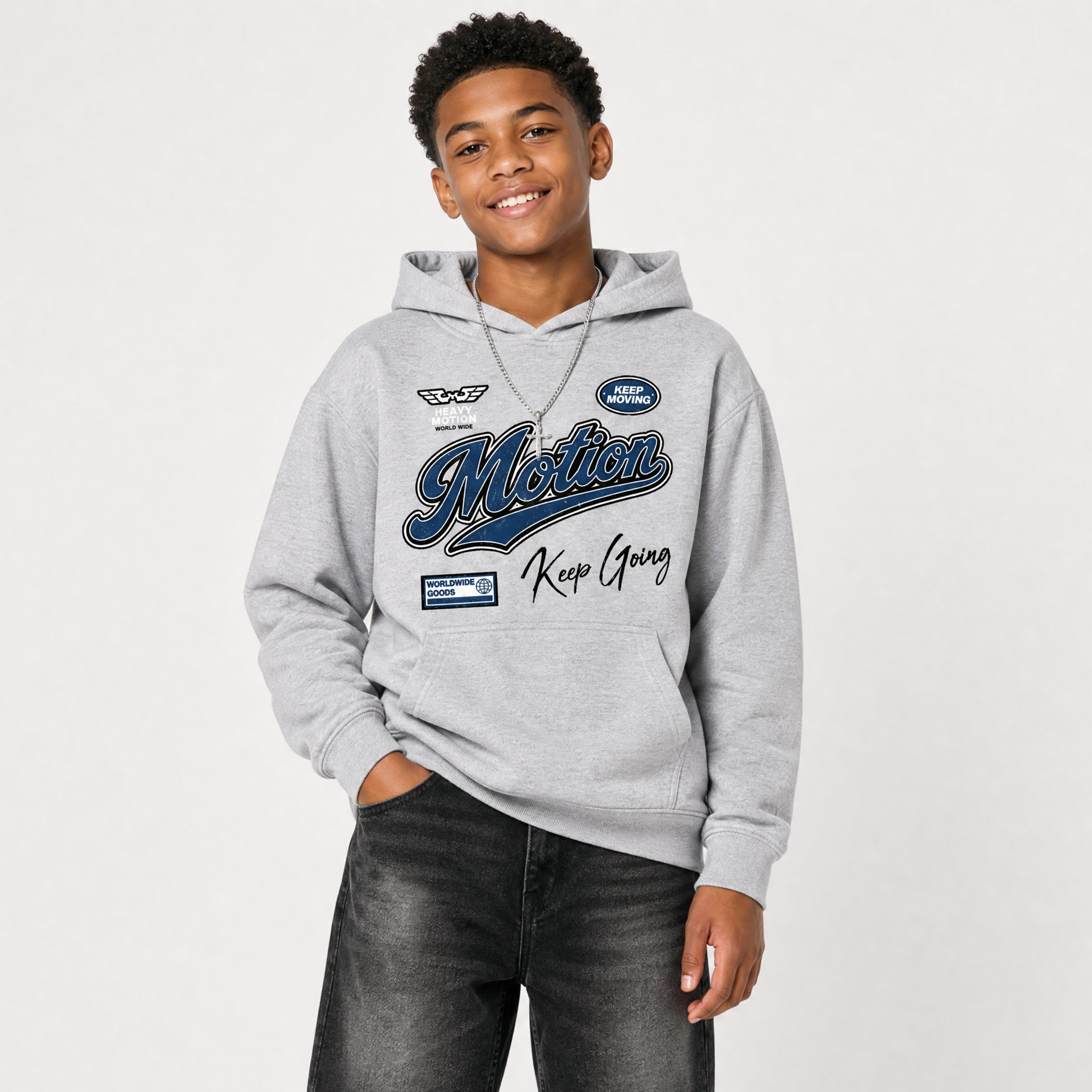 A smiling young man wearing a light gray hoodie with a blue and black 'MOTION Keep Going' graphic print, paired with dark gray jeans, against a plain light gray background.