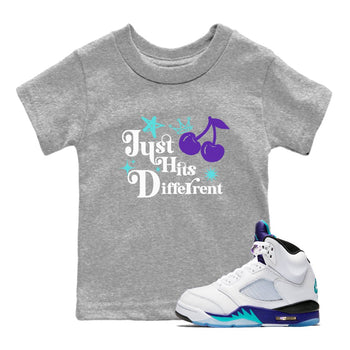 Just Hits Different baby and kids t-shirt crafted for little sneakerheads to shine with the Air Jordan 5 Grape sneakers, displayed in Heather Grey 1.