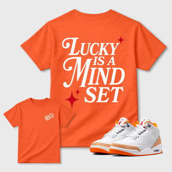 Lucky Is a Mindset graphic t-shirt styled to complete your sneaker outfit with the sneakers, shown in Orange.