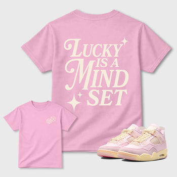 Lucky Is a Mindset graphic t-shirt styled to complete your sneaker outfitwith the Air Jordan 4 Iced Carmine sneakers, shown in Pink.