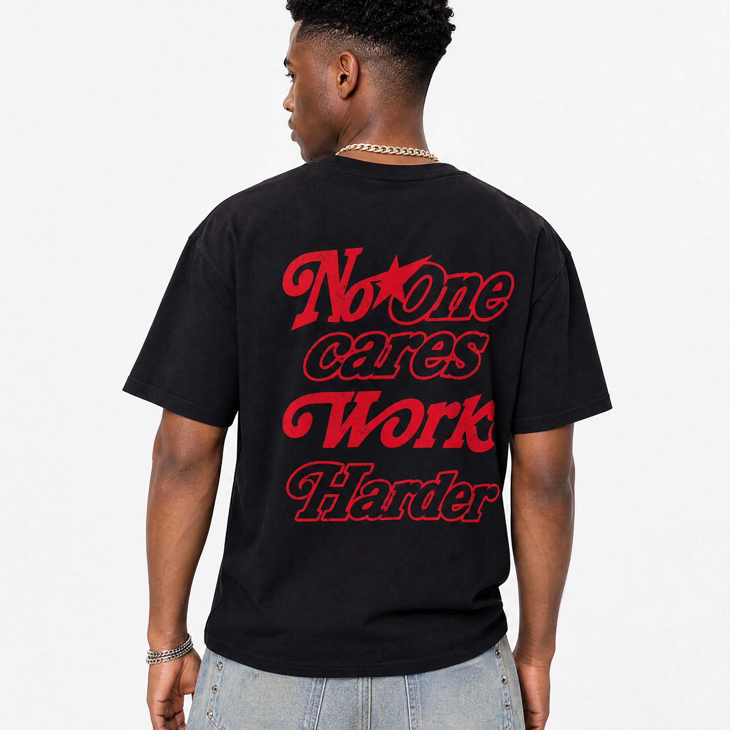 Person wearing a black t-shirt with no one cares work harder text on the back, standing against a plain background