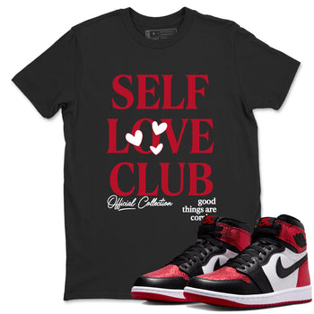 Self Love Club sneaker match t-shirt styled to complete your fit with the Air Jordan 1 Ruby sneakers, shown in Black 1.