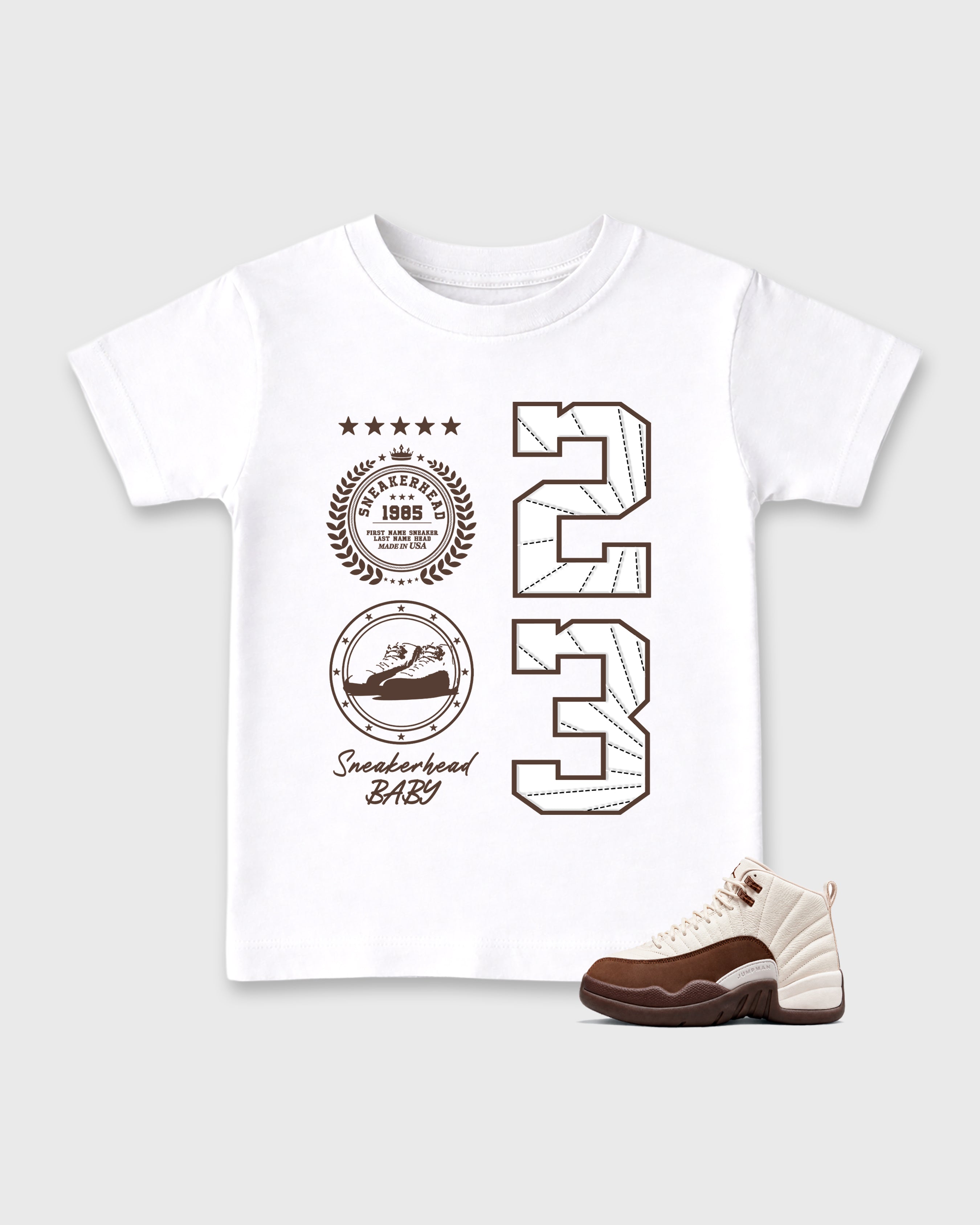 Sneaker Emblem Baby & Kids Graphic T-Shirt featuring original artwork designed to match the Air Jordan 12 Fireside. White 1 Kids Graphic Tee.