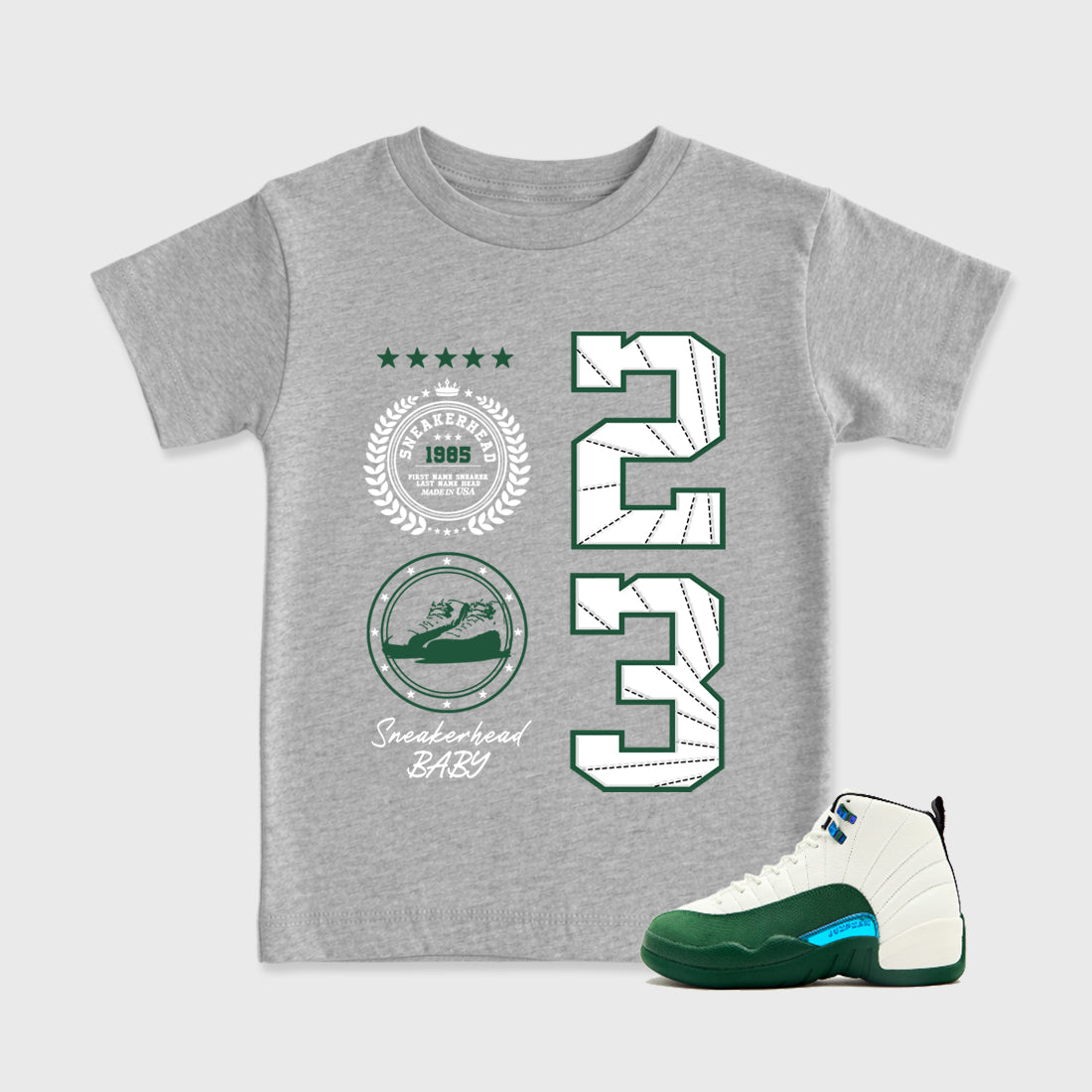 Sneaker Emblem Baby & Kids Graphic T-Shirt featuring original artwork designed to match the Air Jordan 12 Summit Green. Heather Grey 1 Kids Graphic Tee.