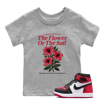 The Flower Or The Soil baby and kids t-shirt crafted for little sneakerheads to shine with the Air Jordan 1 Ruby sneakers, displayed in Heather Grey 1.