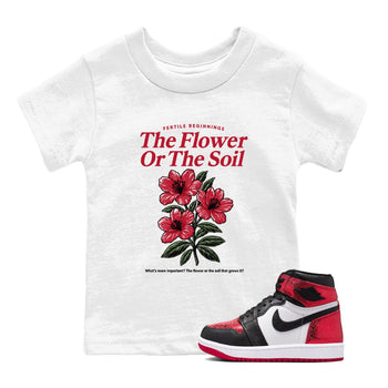The Flower Or The Soil baby and kids t-shirt crafted for little sneakerheads to shine with the Air Jordan 1 Ruby sneakers, displayed in White 1.