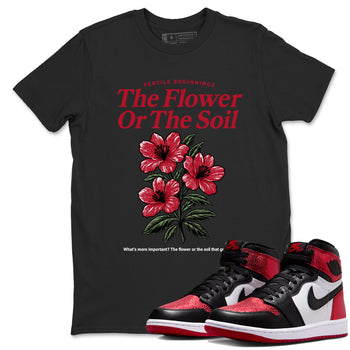 The Flower Or The Soil sneaker match t-shirt styled to complete your fit with the Air Jordan 1 Ruby sneakers, shown in Black 1.