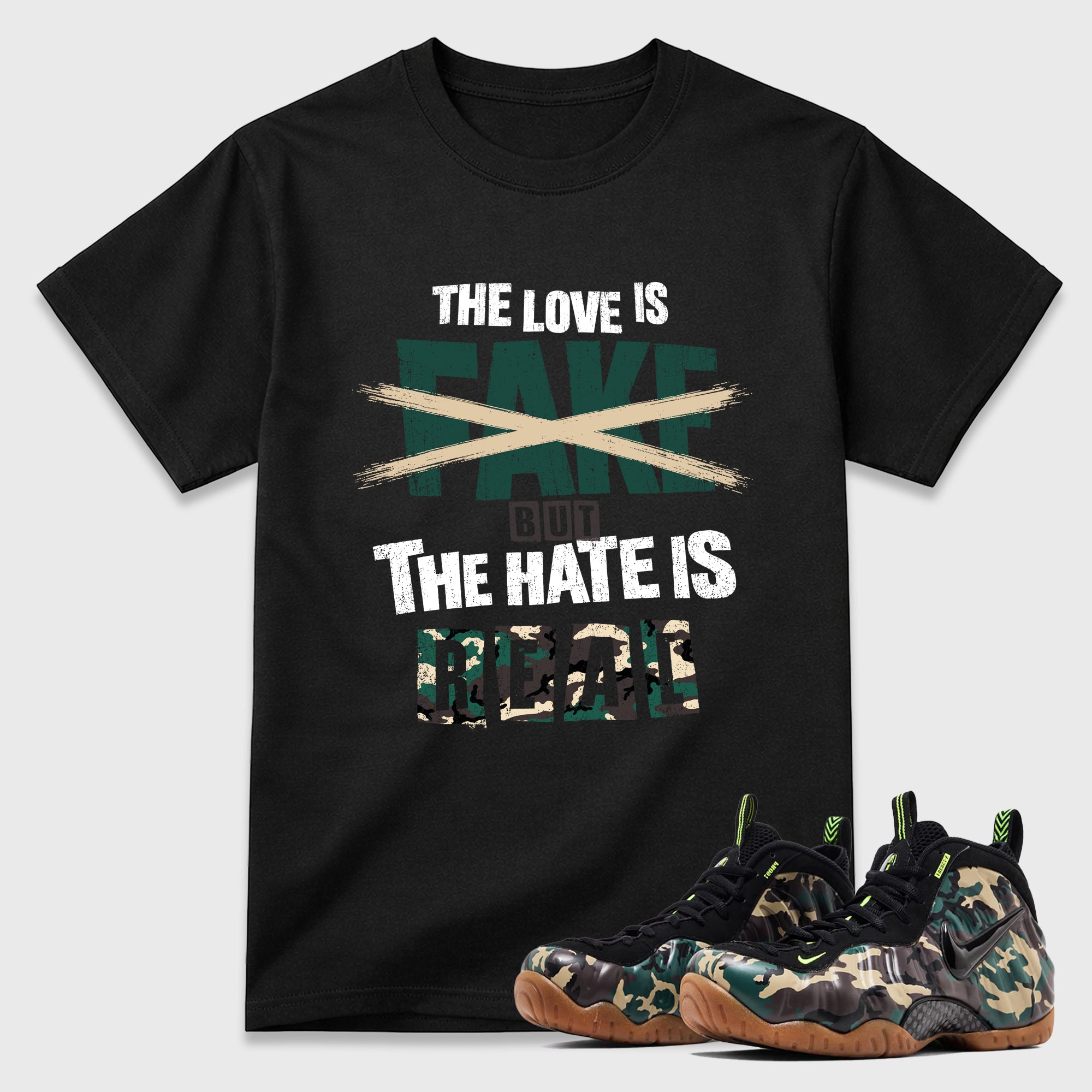 The Love is Fake But the Hate is Real Graphic T-Shirt featuring original streetwear artwork designed to match the Air Foamposite Pro Green Camo. Black 1 Graphic T-Shirt.