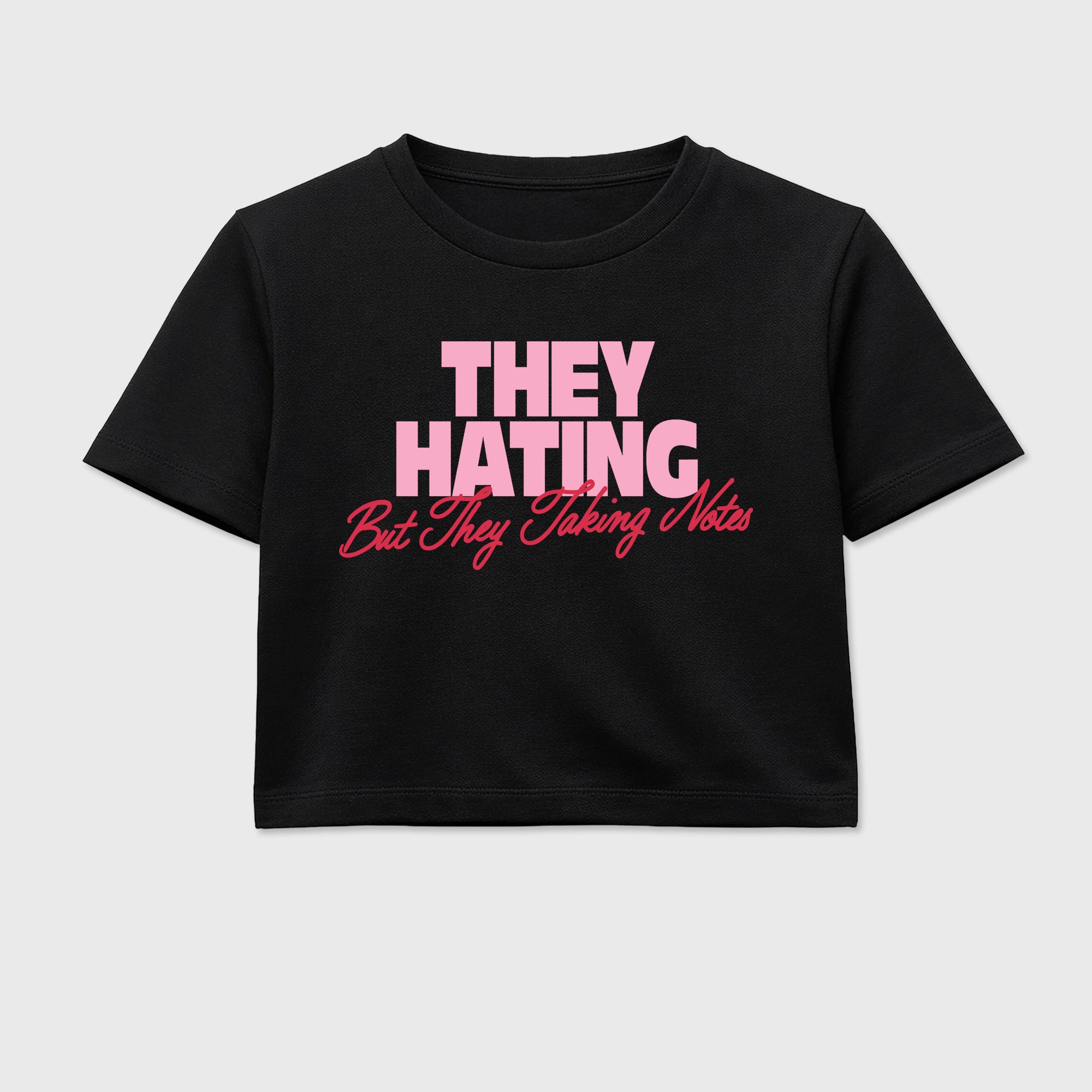 They Hating But Taking Notes women’s crop tee designed to match the Air Jordan 1 Travis Scott Tropical Pink, featuring coordinated Black 2 options for a perfect streetwear vibe.
