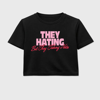 They Hating But Taking Notes women’s crop tee designed to match the Air Jordan 1 Travis Scott Tropical Pink, featuring coordinated Black 2 options for a perfect streetwear vibe.
