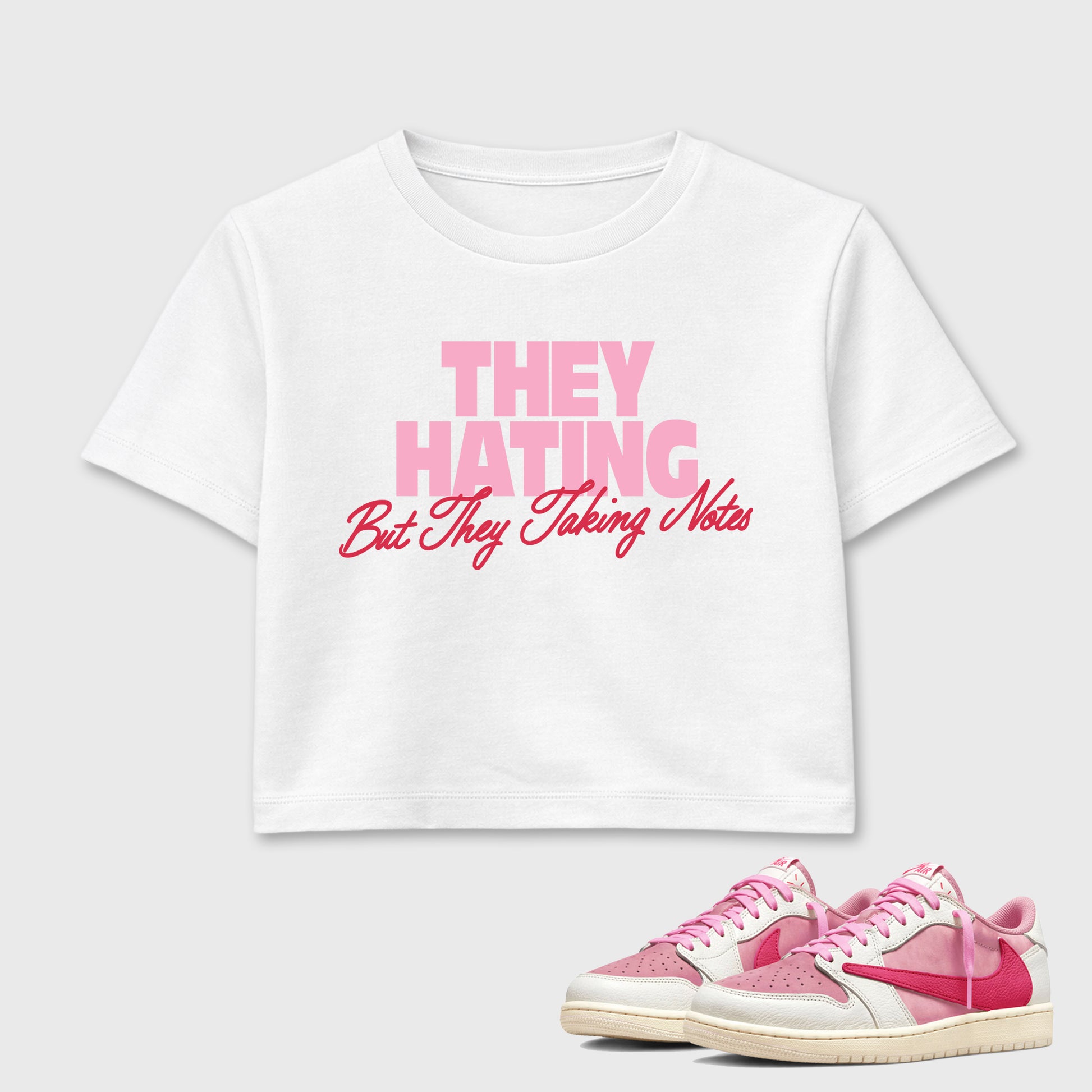 They Hating But Taking Notes women’s crop tee designed to match the Air Jordan 1 Travis Scott Tropical Pink, featuring coordinated White 1 options for a perfect streetwear vibe.