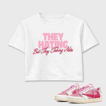 They Hating But Taking Notes women’s crop tee designed to match the Air Jordan 1 Travis Scott Tropical Pink, featuring coordinated White 1 options for a perfect streetwear vibe.