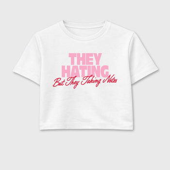 They Hating But Taking Notes women’s crop tee designed to match the Air Jordan 1 Travis Scott Tropical Pink, featuring coordinated White 2 options for a perfect streetwear vibe.