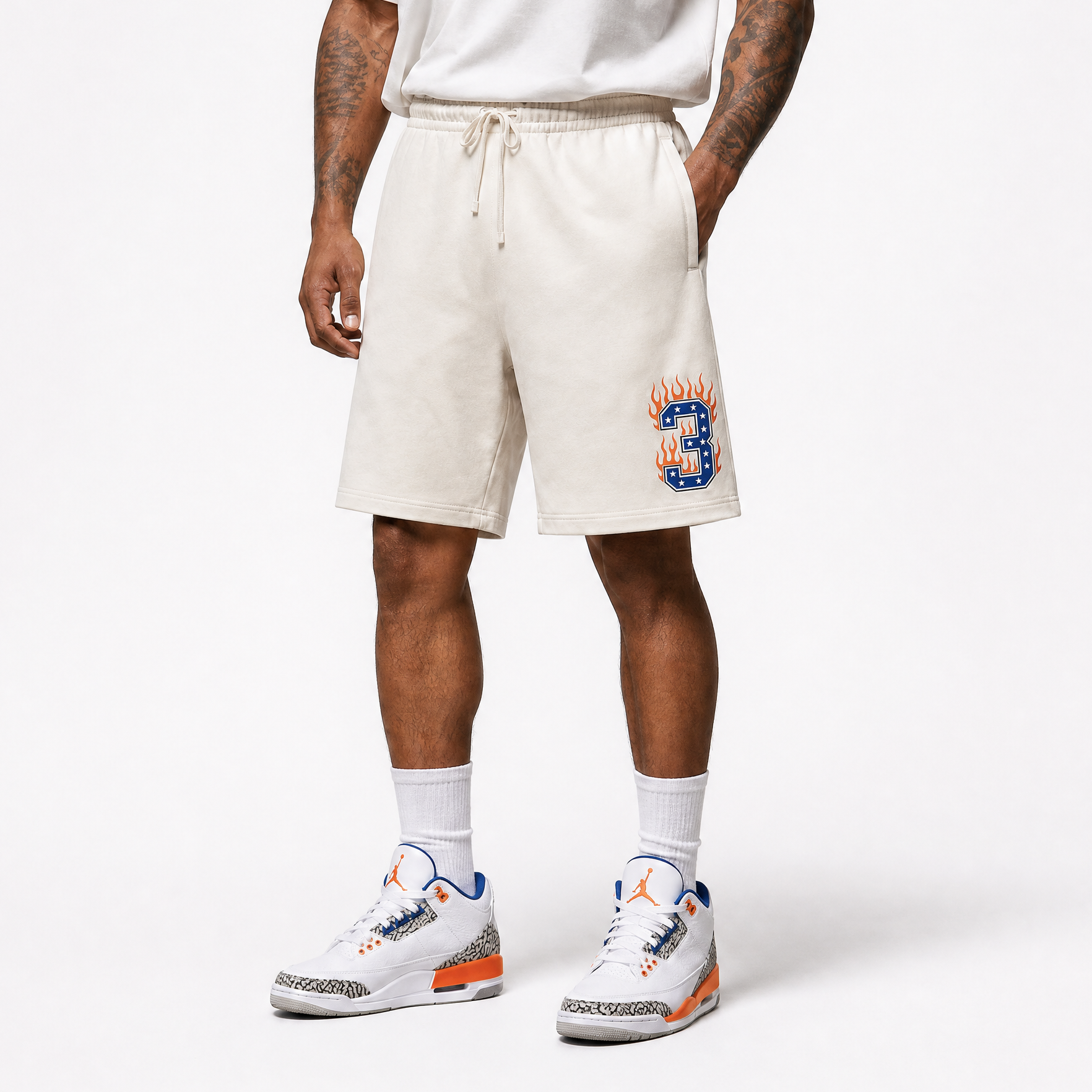 Person wearing cream shorts with a design and white sneakers on a white background