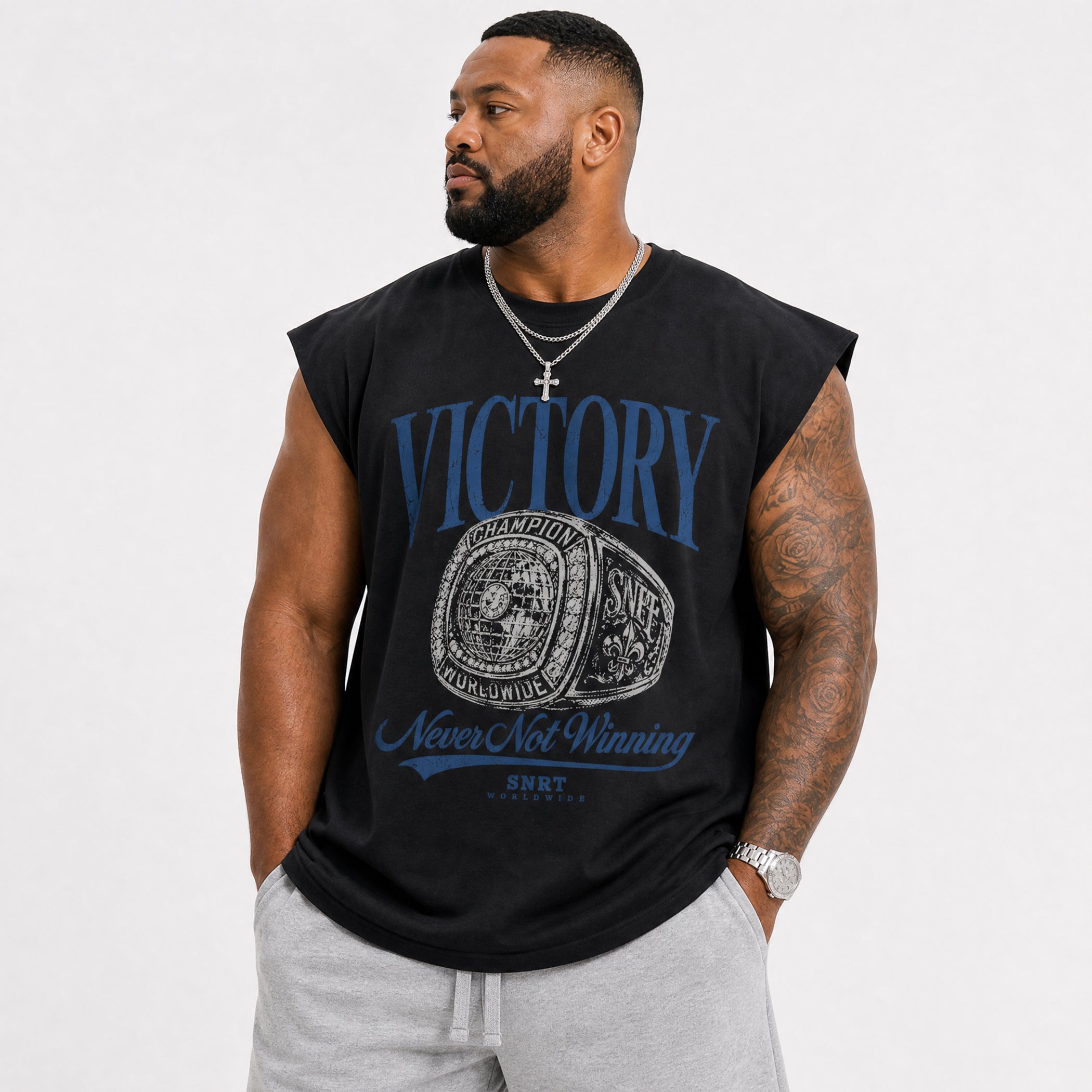 A man wearing a black sleeveless muscle t-shirt with a blue and white championship belt graphic and the words 'VICTORY' and 'Never Not Winning'.