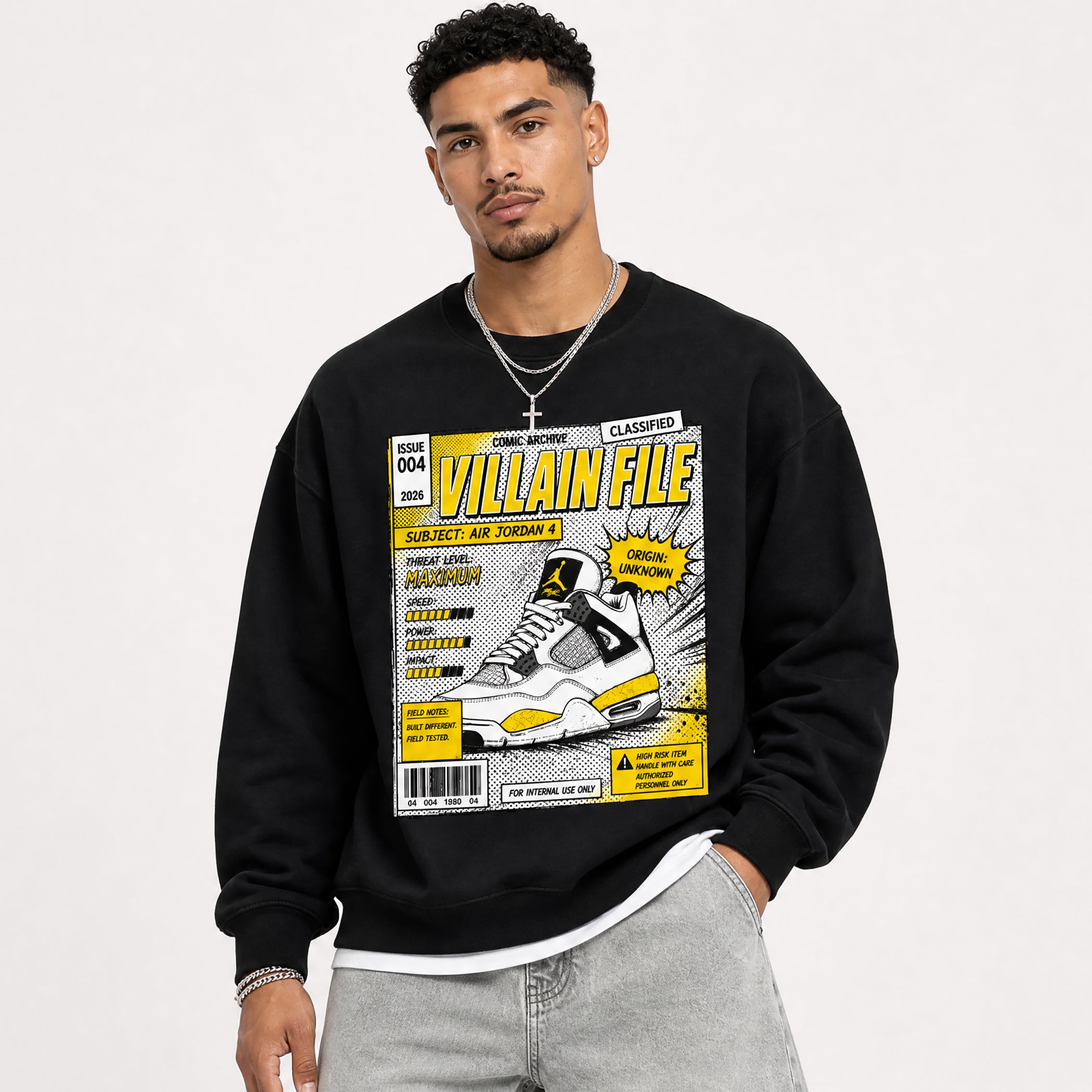 A man wearing a black crewneck sweatshirt with a large comic-book style graphic on the front that reads 'VILLAIN FILE' and shows a sneaker illustration. The background is a clean white studio backdrop.